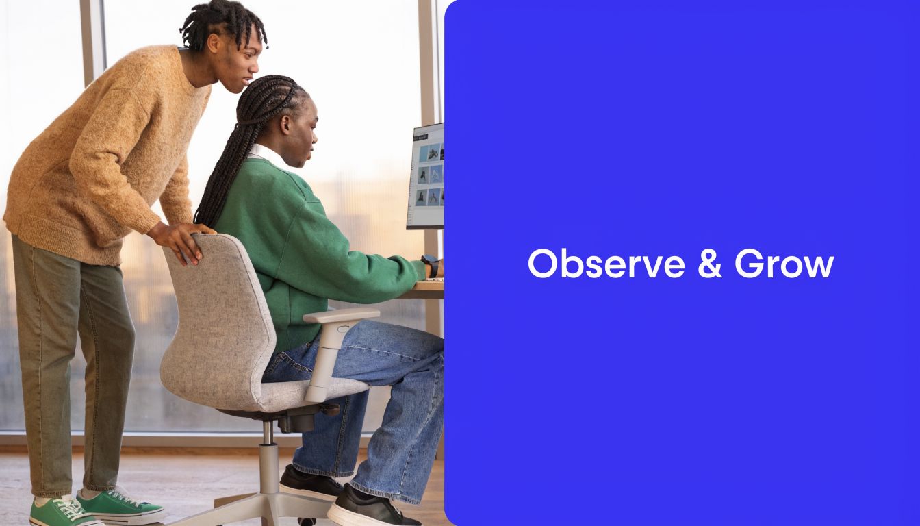 A young person job shadowing their colleague at a computer in a modern office space.