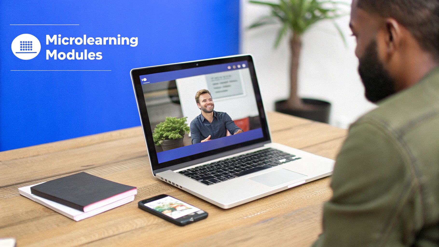 A man views a laptop screen displaying a smiling instructor, with "Microlearning Modules" on a blue background.