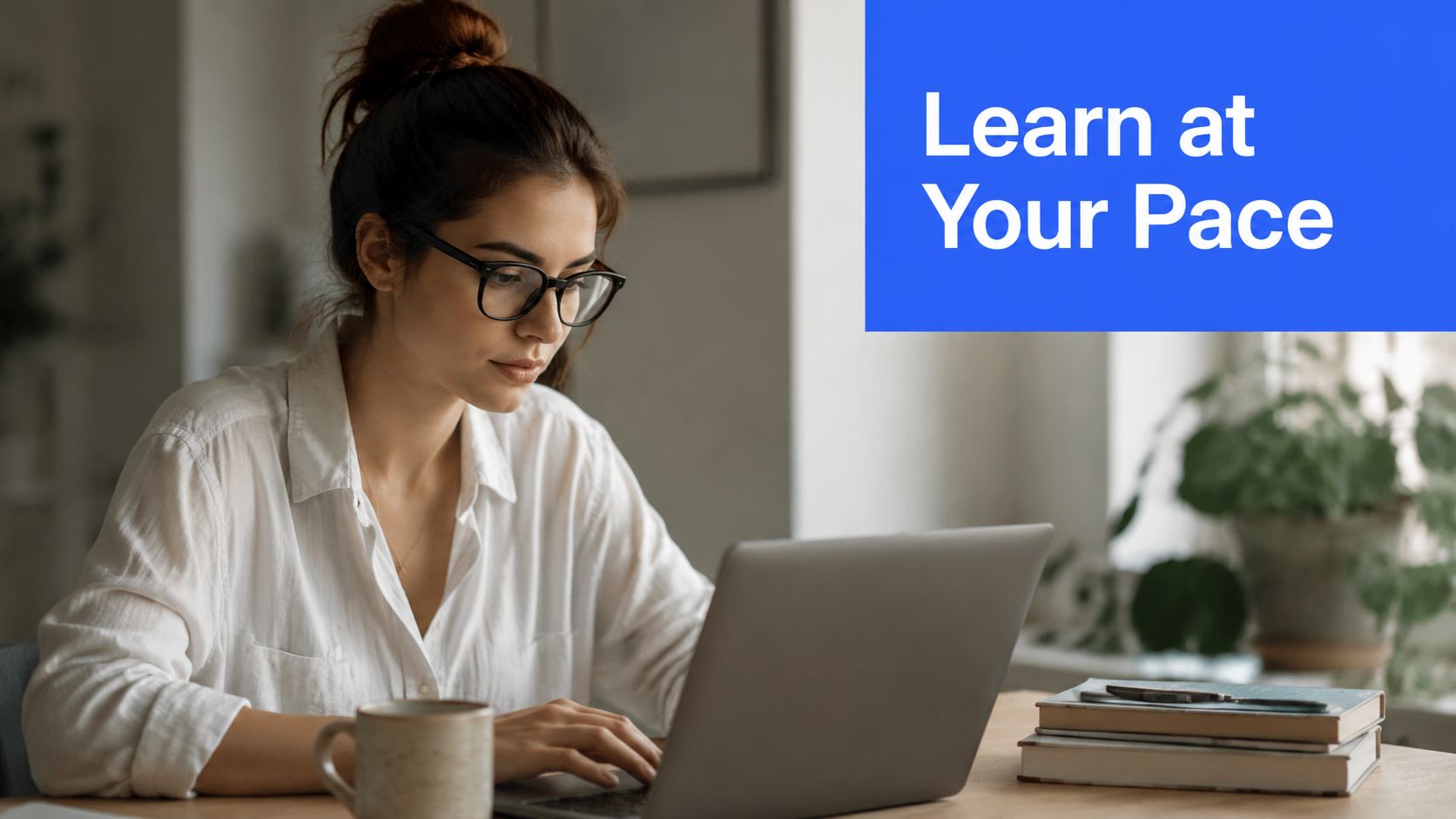A woman wearing glasses typing on her laptop while learning at home at her own pace.