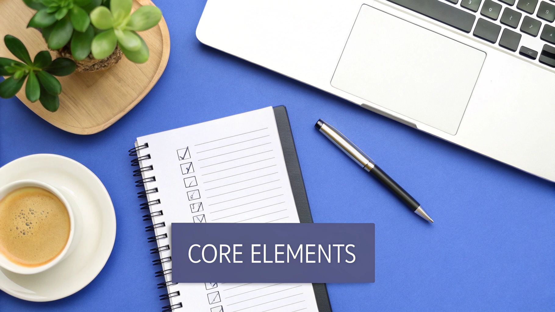 Overhead view of a blue desk with a laptop, notebook, pen, coffee, plant, and 'CORE ELEMENTS' text.