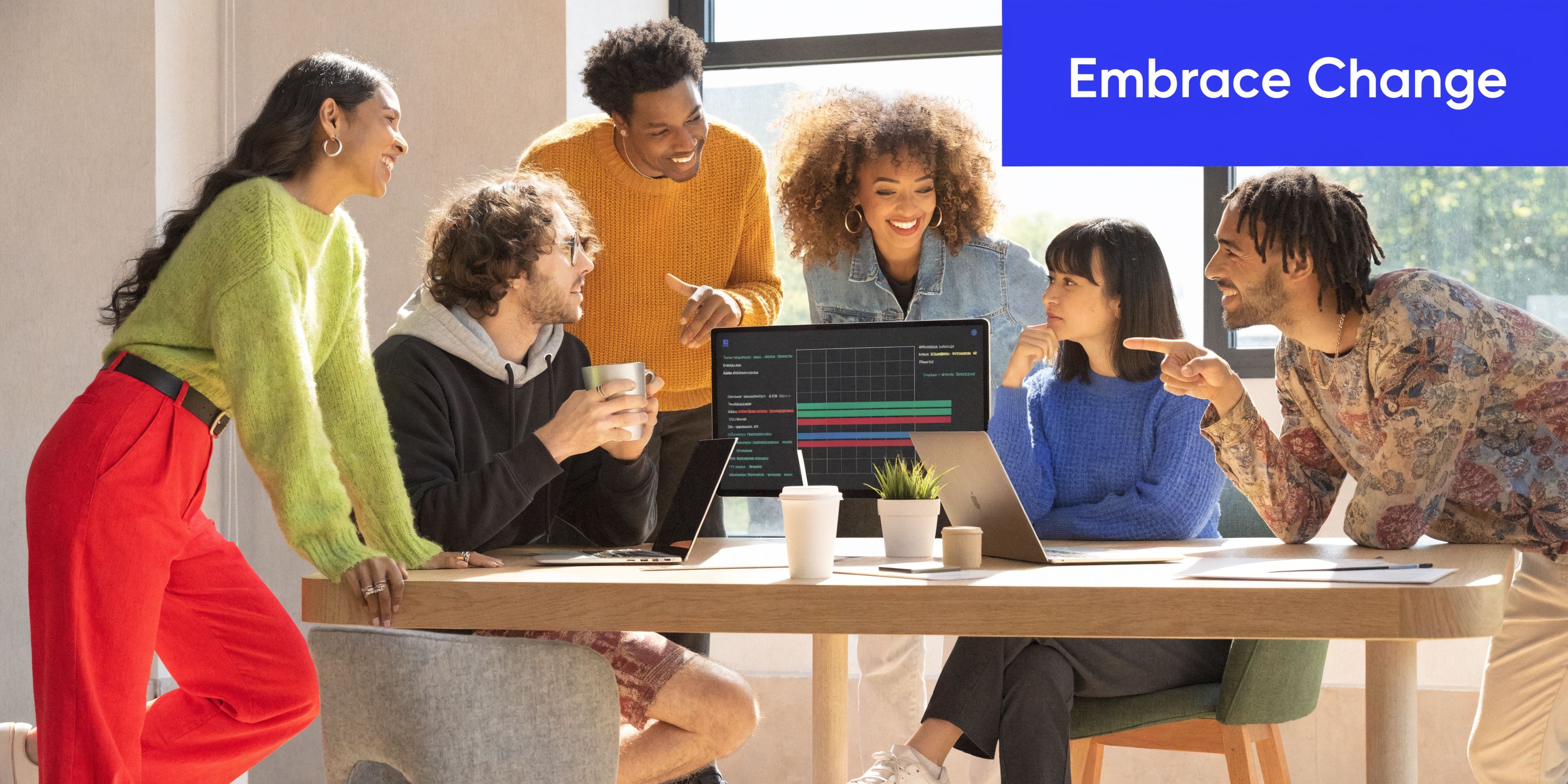 A diverse group of professionals collaborating around a table while analyzing data on a computer screen.